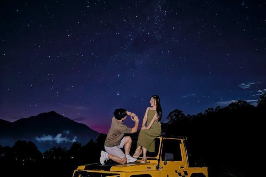 Two people sitting on a yellow vehicle under a starry night sky. 4