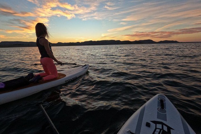 A person on a paddleboard in a body of water during sunset. 2