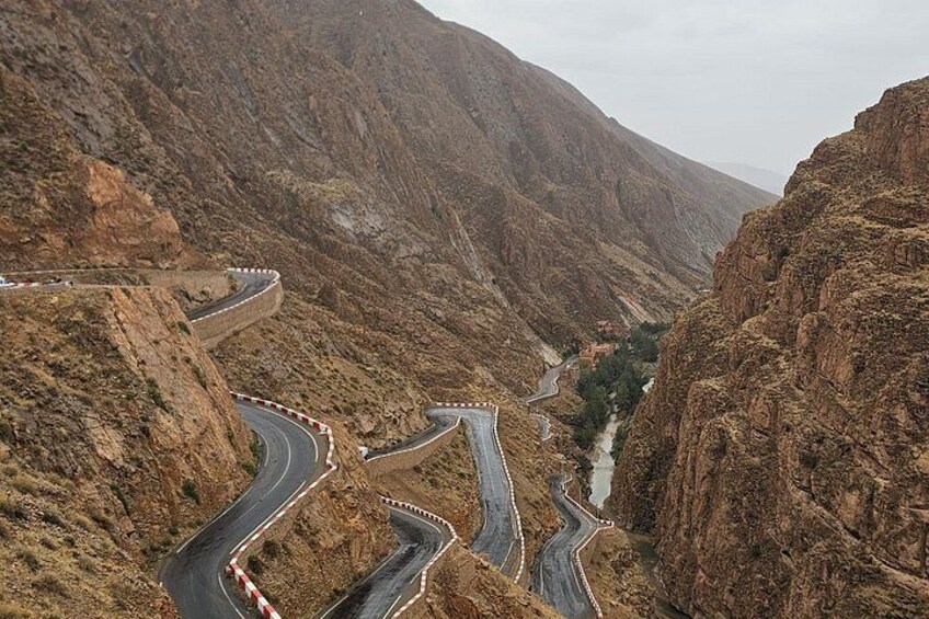 A winding mountain road with guardrails, surrounded by rugged terrain and sparse vegetation. 4