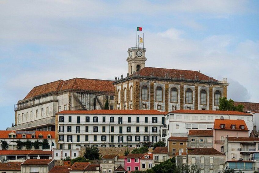 Un edificio histórico con una torre de reloj, rodeado de otros edificios con tejados de tejas rojas. 4