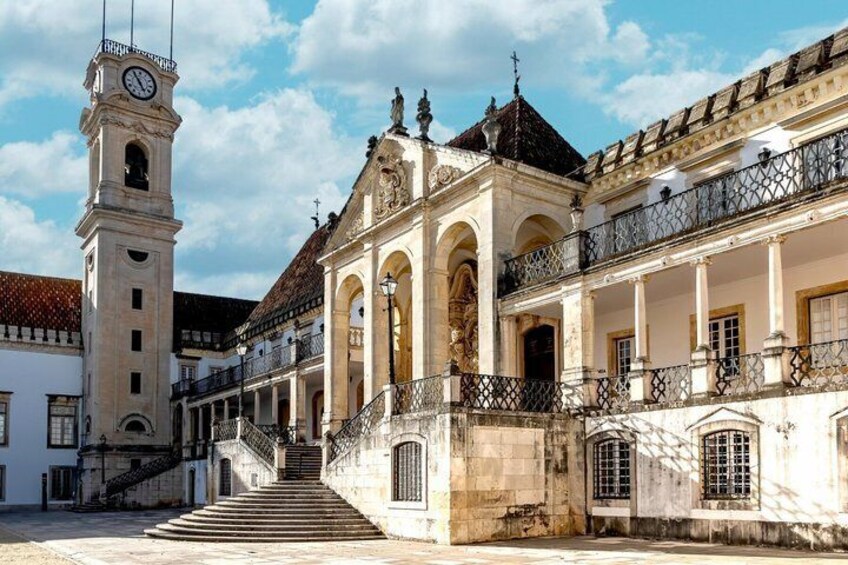 Un bâtiment historique doté d’une tour horlogée, d’un escalier menant à l’entrée et d’un balcon orné de balustrades en fer forgé. 2