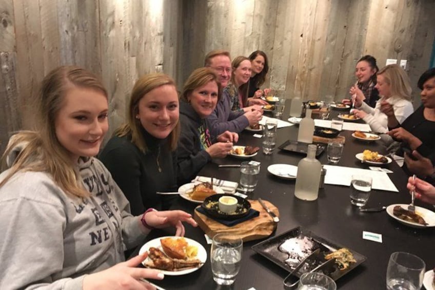 A group of people sitting around a table with food and drinks. 1