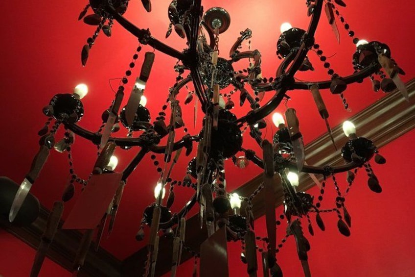 A chandelier with multiple arms and hanging ornaments against a red background. 4
