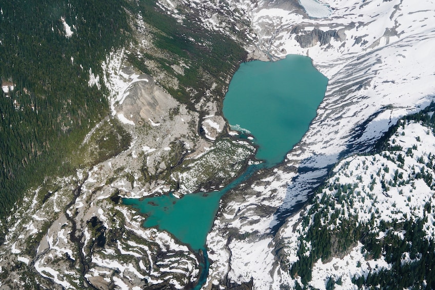 Un lago glaciar rodeado de montañas nevadas y bosques densos. 4