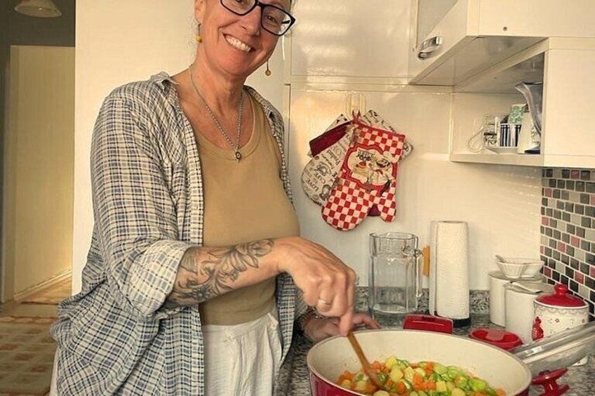 A person cooking in a kitchen with a pot on the stove, a checkered oven mitt, and a tiled backsplash. 4