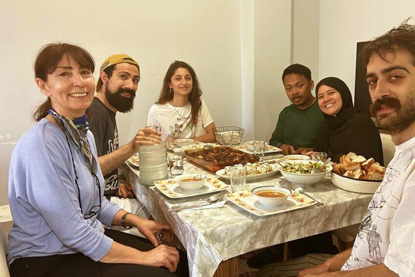A group of people seated around a table with various dishes and a pitcher. 2