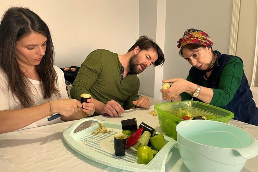 Three people sitting at a table with a tray of food, including green vegetables and a bowl. 3