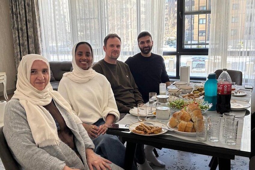 A group of people seated around a table with food and drinks. 1