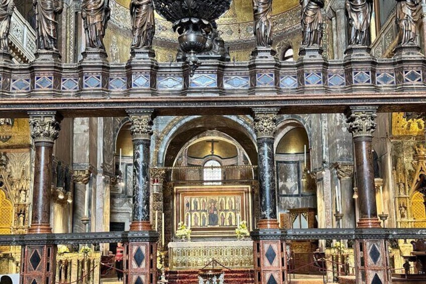 An ornate church interior with detailed carvings, golden accents, and statues. 4