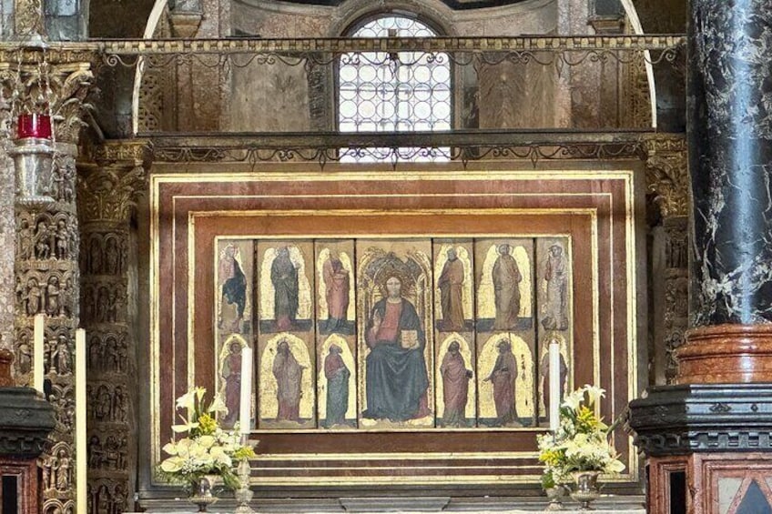 An ornate religious iconostasis with a central figure, flanked by two candle holders and a vase of flowers. 5