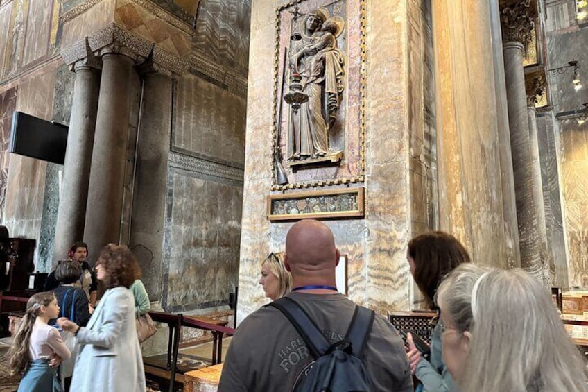 A group of people inside a church with marble columns and a statue on the wall. 3