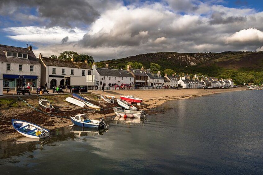 A coastal town with boats docked along the shore, buildings, and a beach. 2