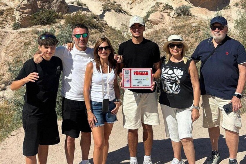 Un grupo de personas de pie sobre un sendero de tierra con terreno rocoso al fondo. 1