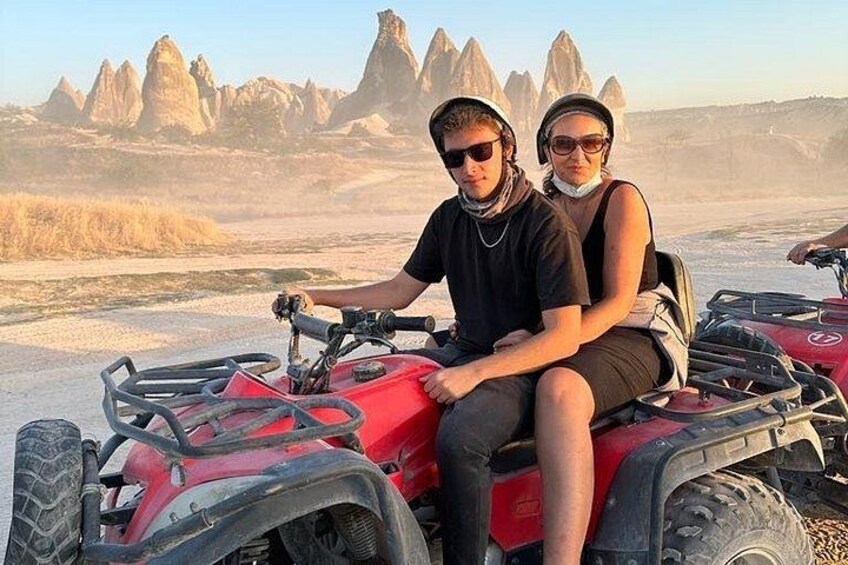 Dos personas en un vehículo todo terreno rojo en un paisaje desértico con formaciones rocosas. 2