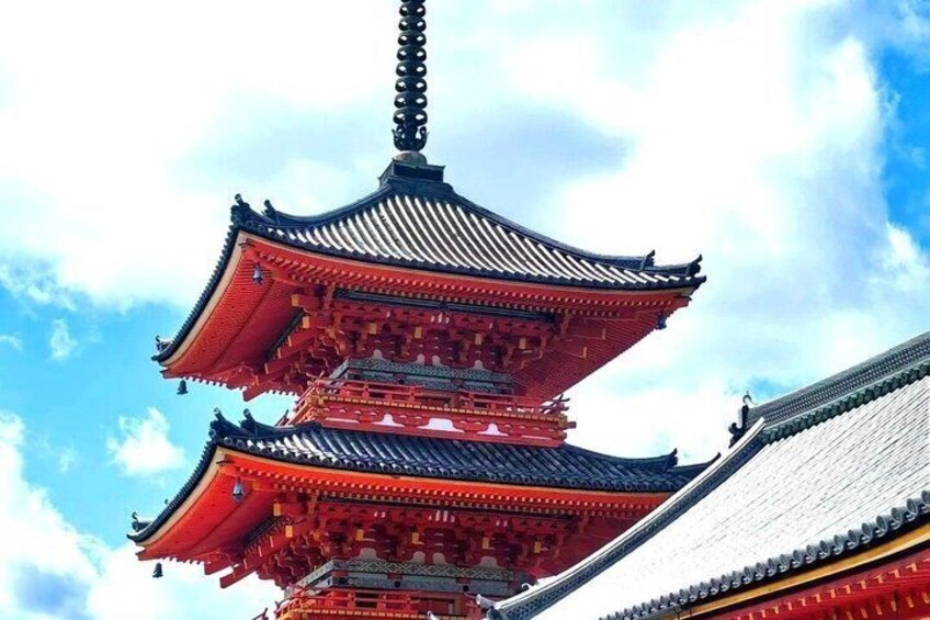 A traditional multi-tiered pagoda with red and black roofing against a partly cloudy sky. 4