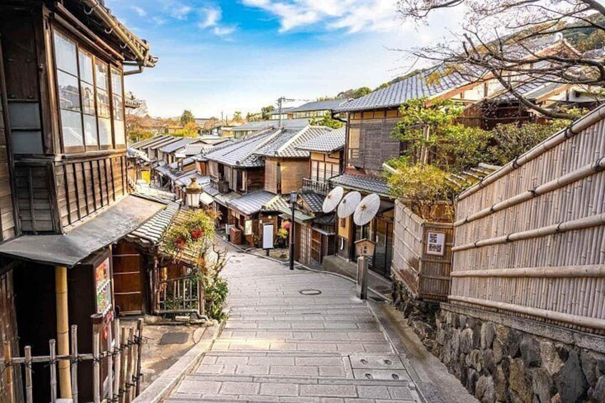 A traditional Japanese street with wooden buildings, stone walls, and tiled roofs. 5