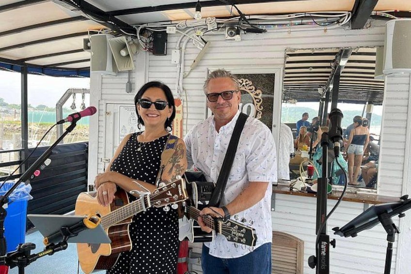 Två personer spelar gitarr på en båt, och de har mikrofoner och en högtalare. 2