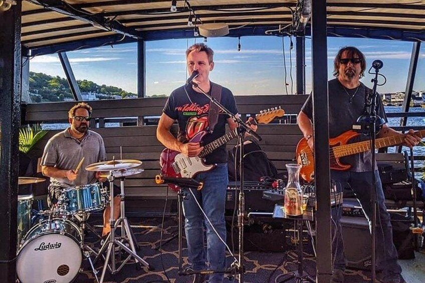 Una banda tocando en un barco con vista al agua. 2