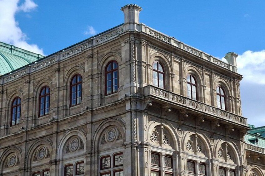 Un bâtiment historique doté d’éléments architecturaux raffinés, notamment des fenêtres en arc de cercle et des décorations en pierre. 4