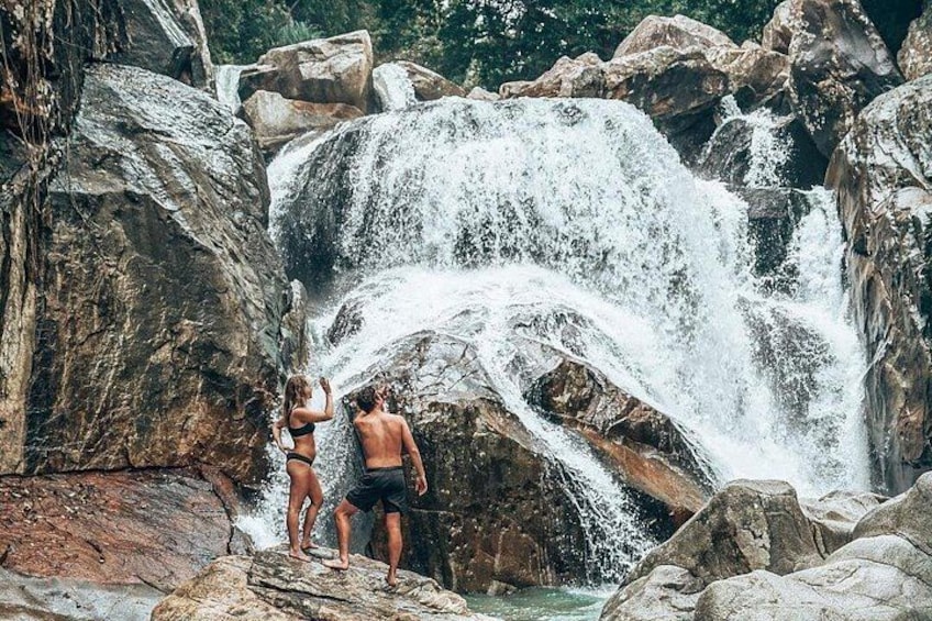 Een waterval met mensen die op rotsen staan. 1