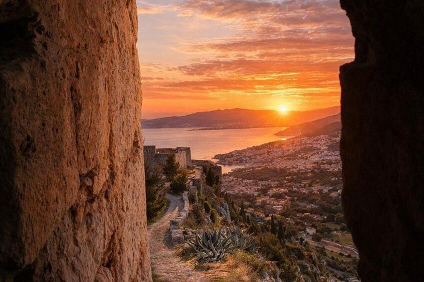 A sunset over a coastal city with a historic fortification and a clear view of the sea. 2