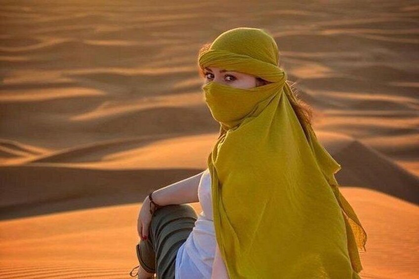 Eine Person sitzt auf einer Sanddüne in einer Wüstenlandschaft. 4