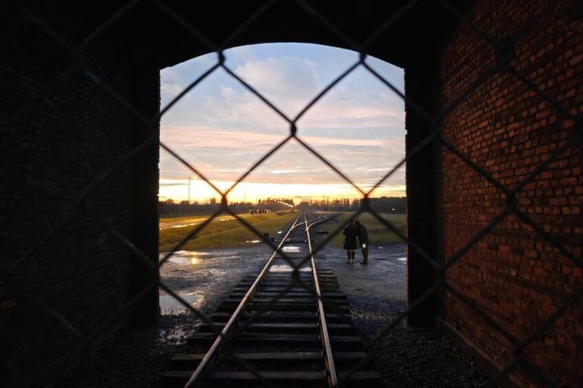 A railway track leading to a sunset with a brick wall on the right. 2