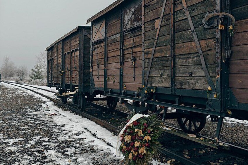 A snow-covered railway track with a wooden train car and a floral arrangement. 2