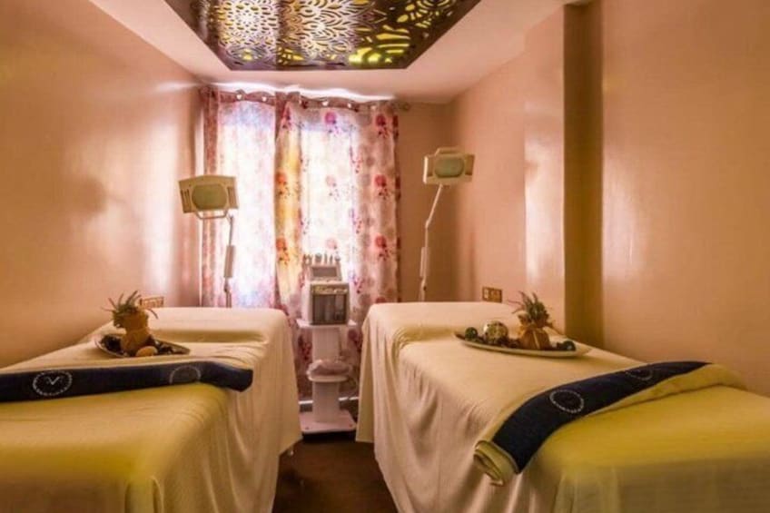 A room with two beds, each with a tray of fruits and a small statue. 3