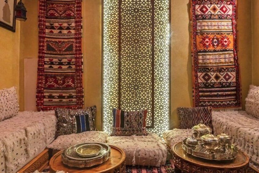 A traditional room with patterned textiles, cushions, and ornate metal trays. 2