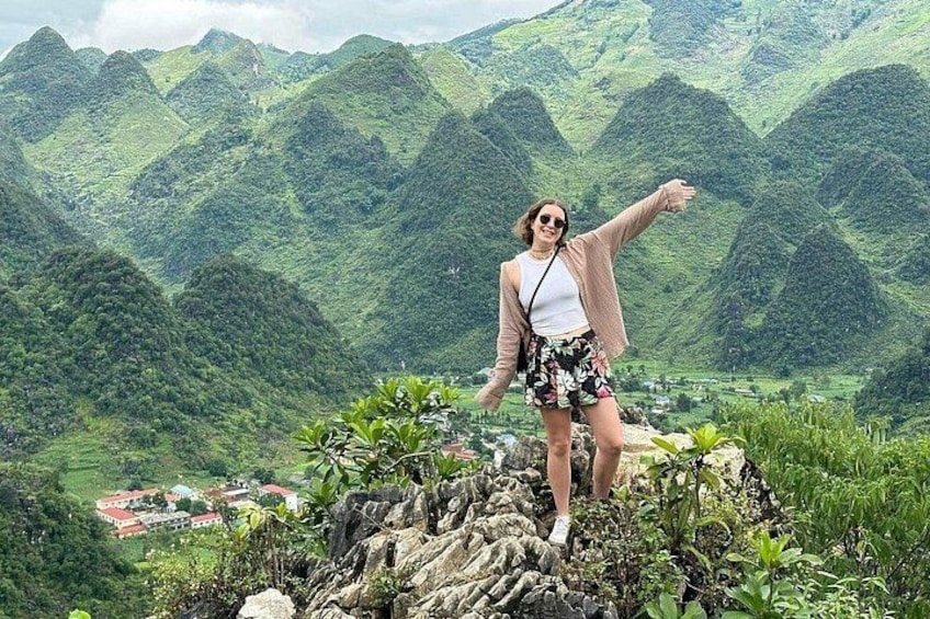 A person standing on a rocky outcrop with a mountainous landscape in the background. 1