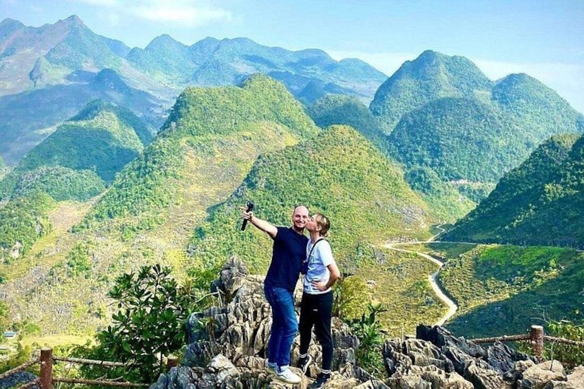 A person taking a selfie with a child on a rocky outcrop overlooking a mountainous landscape. 5