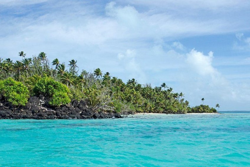 A tropical island with turquoise waters, dense palm trees, and rocky outcrops. 2