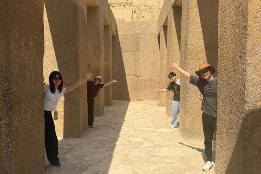 A group of people in an ancient stone corridor with columns. 4