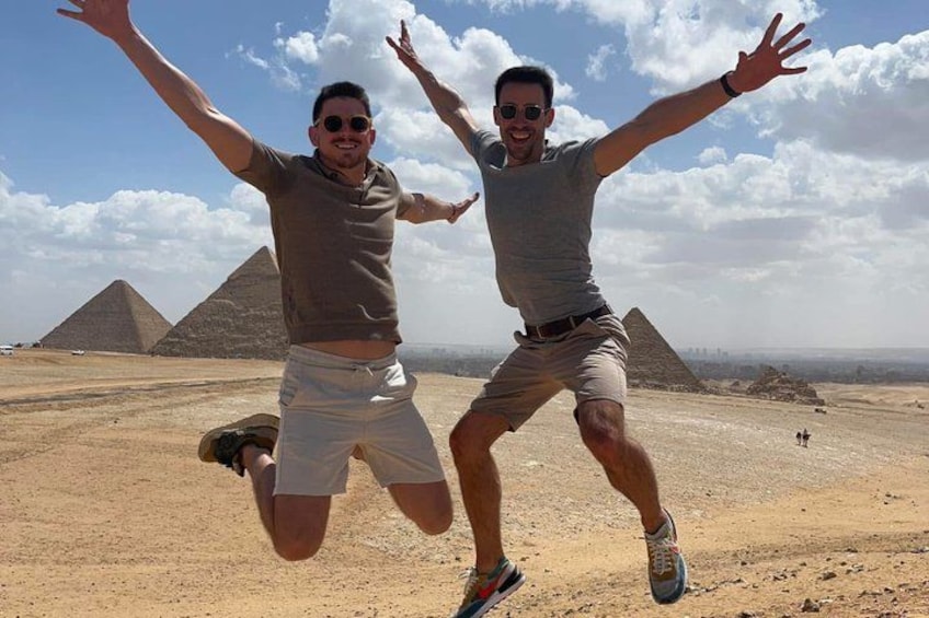 Two people jumping in front of pyramids. 2