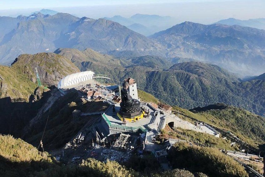A mountainous landscape with a temple complex, including a large white building and a central structure with a spire. 2