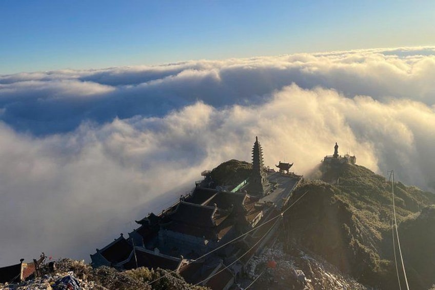 A mountain peak with traditional architecture, a temple, and a statue. 4