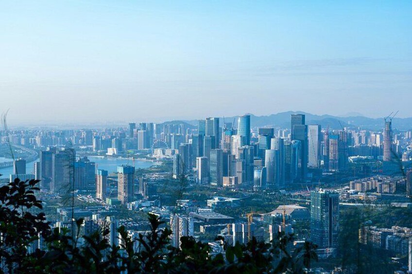 A cityscape with numerous high-rise buildings, a river, and distant mountains. 2