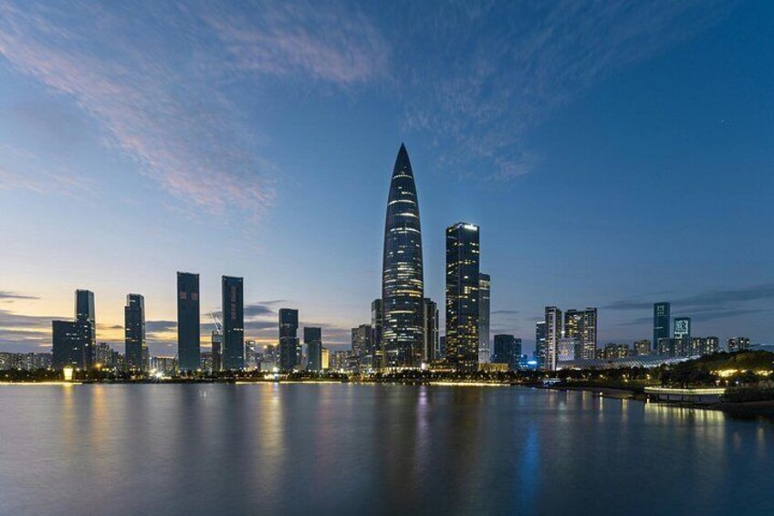 A city skyline at dusk with illuminated buildings reflecting on the water. 4