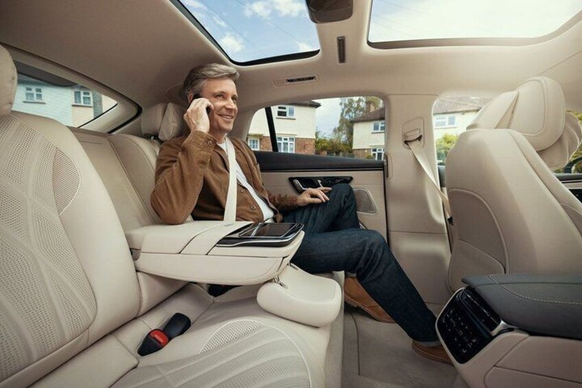 A person sitting in a car with a sunroof, using a smartphone and a tablet. 2