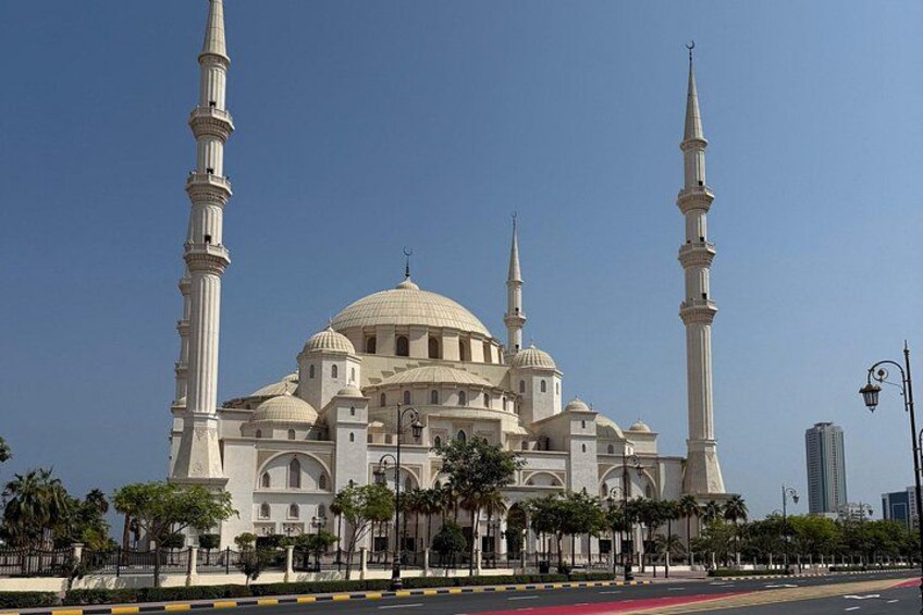 Eine große Moschee mit mehreren Kuppeln und Minaretten, umgeben von einem Zaun und Palmen. 5