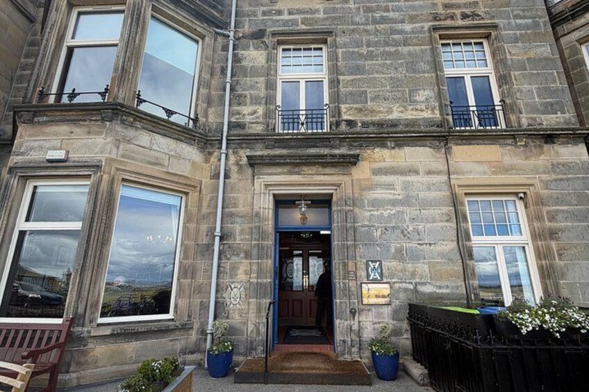 A stone building with a blue door, large windows, and potted plants. 3