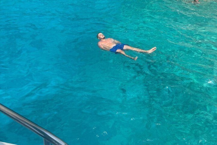A person floating in a clear blue pool. 3