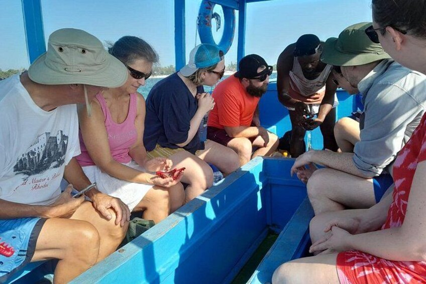 A group of people on a boat with a blue interior, some sitting and others standing, engaged in an activity. 2