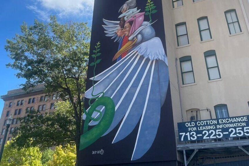 A mural of an angel with wings on a building, with a phone number for the Old Cotton Exchange. 4