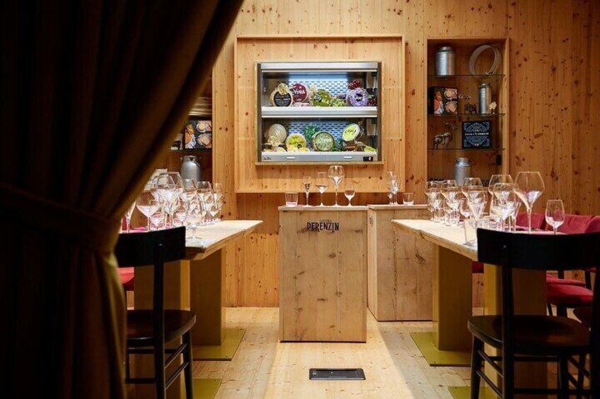 Een houten interieur met twee tafels, elk met wijnglazen en een koelkast vol etenswaren. 4