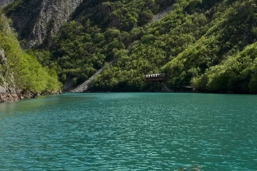 A turquoise lake surrounded by lush green hills. 2