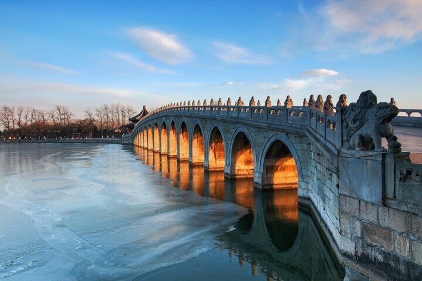 Un pont de pierre à arches enjambant une rivière gelée, orné de statues sur les côtés, avec un ciel dégagé. 4