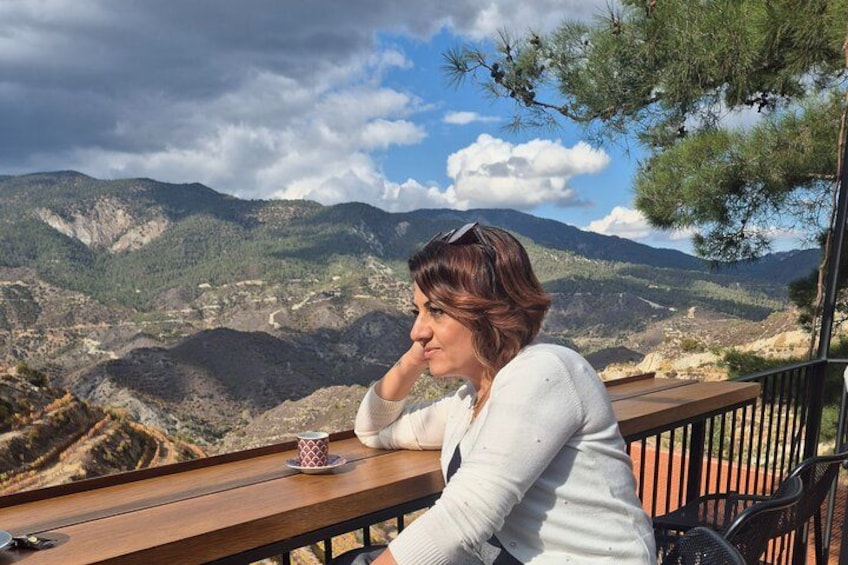Una persona sentada en una mesa de madera con vistas a una montaña en el fondo. 2