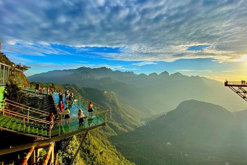 Un pont de verre sur lequel des personnes se promènent, offrant une vue panoramique sur un paysage montagneux. 5